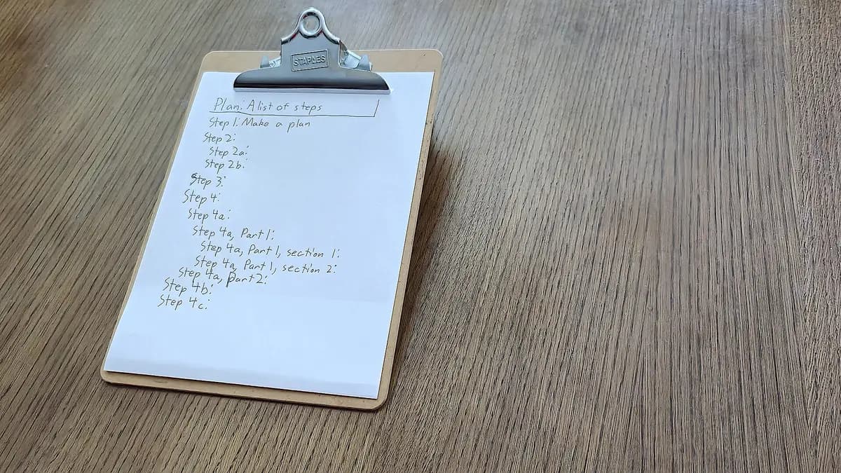 A clipboard on a wooden table holding a handwritten list of numbered steps
