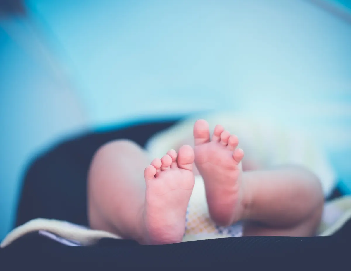 A newborn baby’s bare feet resting on a soft blanket
