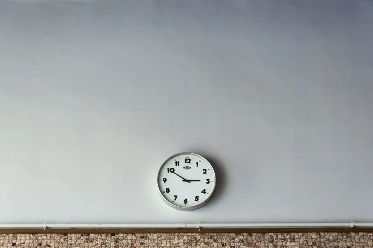 A plain round wall clock on a light gray wall